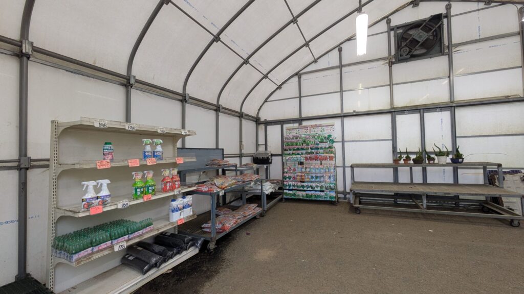 産直センターの内部、棚に飲料水や食品が並んでいる。壁は透明で、施設の構造が見える。