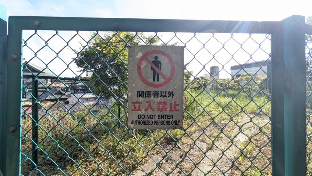 フェンスに取り付けられた「関係者以外立入禁止」の看板が写っています。