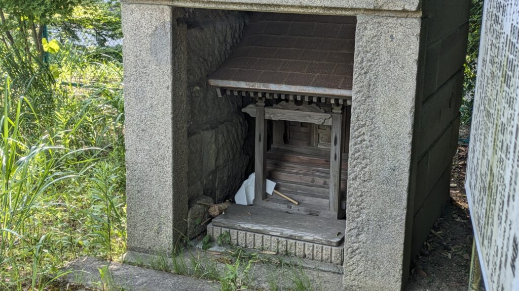 小さな神社のような構造物が草むらの中にあります。