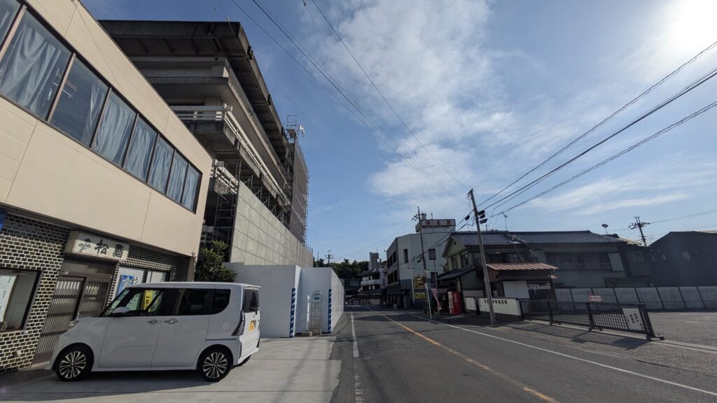 通り沿いの白い車と建物、青空の下の風景