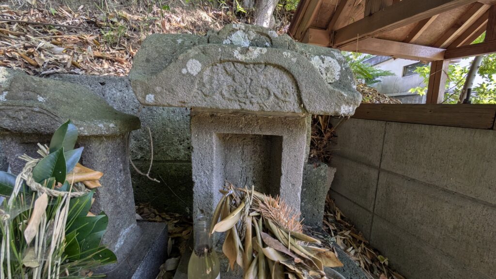 古い石の祠が葉に覆われている。