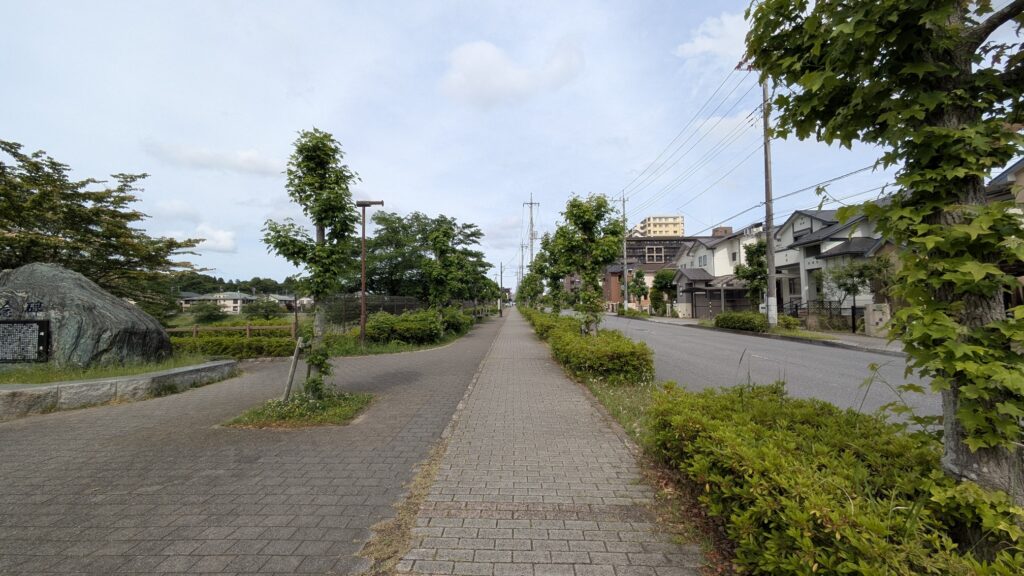 緑の植栽が並ぶ歩道と静かな住宅街の風景
