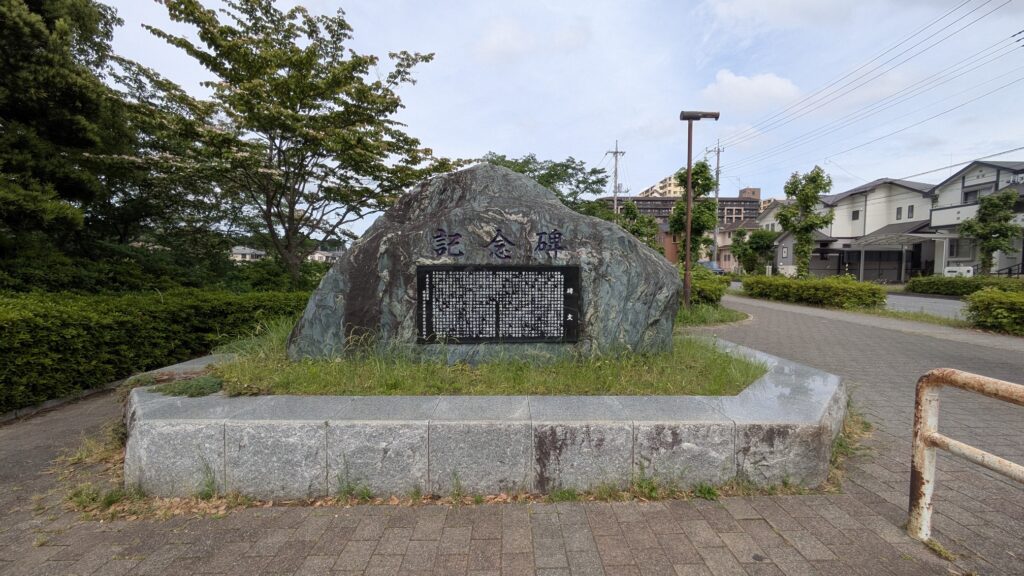 記念碑がある公園の風景、青空と緑の木々に囲まれた石のモニュメント