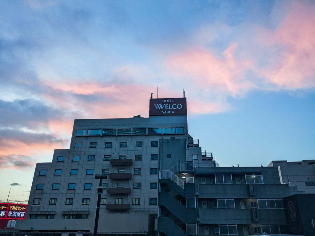 2026年10月撮影・成田市花崎町のホテルウェルコ成田 早朝の空と屋上の看板|営業中