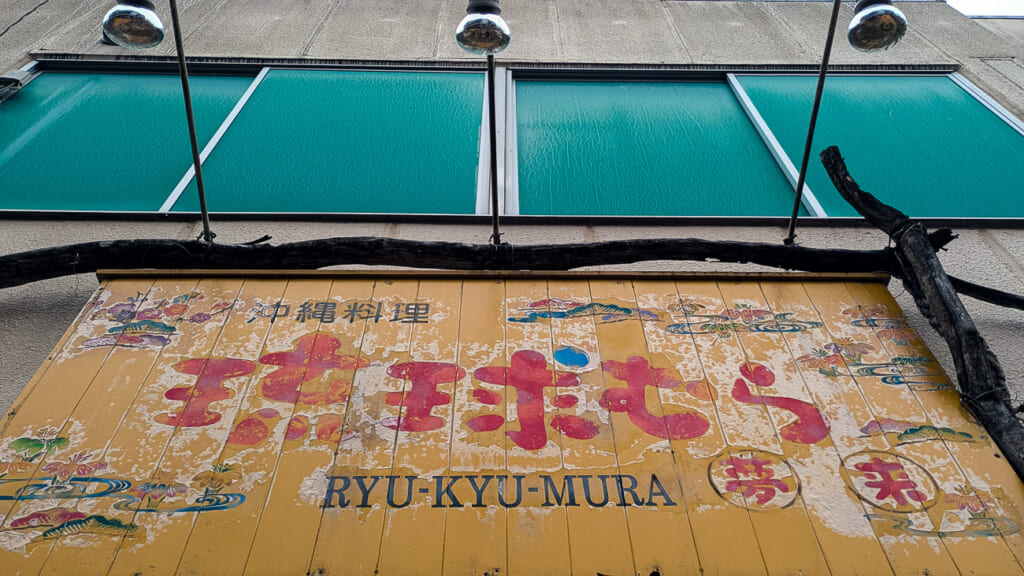 2026年10月撮影・成田市花崎町の開運ビル 沖縄料理 琉球むらの色あせた看板|閉店・建物あり
