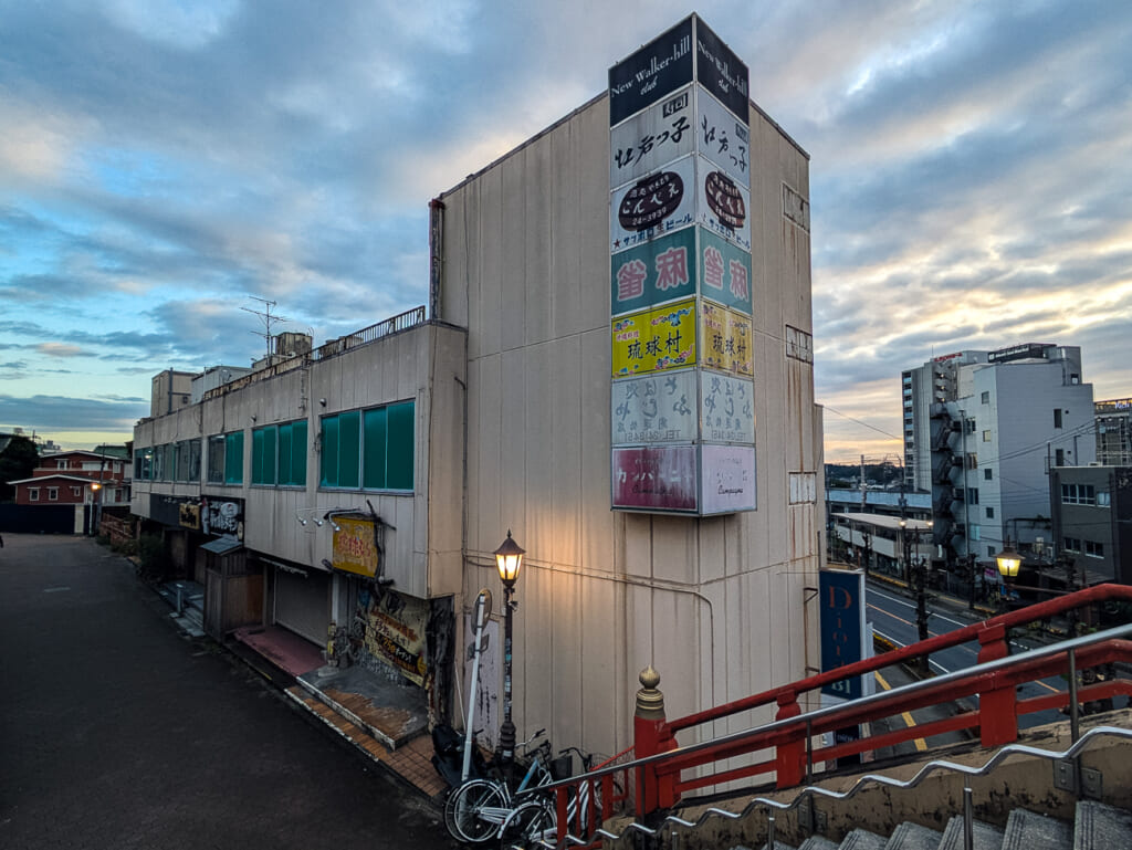 2026年10月撮影・成田市花崎町の開運ビル 開運橋から見た袖看板の塔と路地|現存
